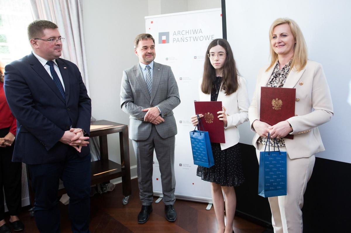 Wyróżniona w konkursie Klaudia Ziętal ze Szkoły Podstawowej im. Jana Pawła II w Drohojowie odebrała nagrodę z rąk wiceministra edukacji i nauki Tomasza Rzymkowskiego oraz dyrektora Archiwów Państwowych Pawła Pietrzyka. Na zdjęciu razem z opiekunem naukowym Magdaleną Wilk-Perłak.
<br/>fot.M. Gmitruk
