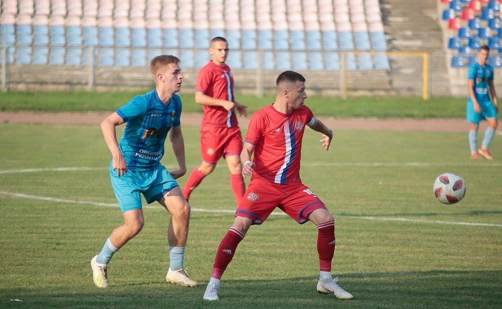 Kapitan Polonii Krystian Kazek (na pierwszym planie, czerwony strój) sprawnie dowodził drugą linią przemyślan w meczu w Pruchniku.<br/>fot.Kamil Krukiewicz