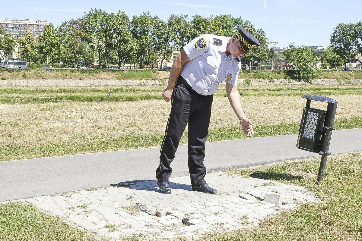 Strażnik miejski pokazuje miejsce po wyrwanej ławce.<br/>fot.Jacek Szwic
