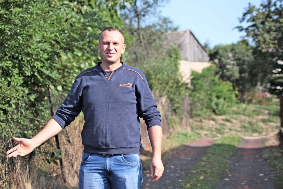 – Gdyby przetarg był zorganizowany przejrzyście, nie miałbym pretensji. Pogodziłbym się z przegraną. Jednak tak nie było – uważa Michał Szczepankiewicz. Mężczyzna stoi na podwórku sąsiada. Za nim wąski wjazd, z którego musi korzystać.  <br/>fot.Roman Kijanka