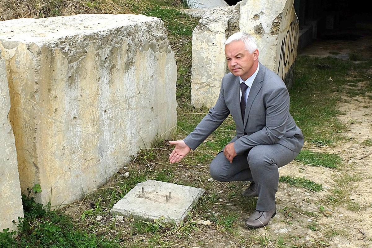 Andrzej Huk, wójt Gminy Przemyśl, pokazuje podstawę po skradzionej tablicy informacyjnej na forcie w Orzechowcach.<br/>fot.Jacek Szwic
