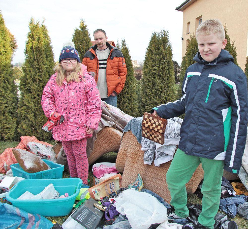 Maciej Lisowski z córką i synem przed stertą zniszczonych ubrań, mebli, zabawek i sprzętu domowego. – Trudno wytłumaczyć dzieciom, że większość zabawek musi iść na śmietnik – mówi.<br/>fot.Roman Kijanka