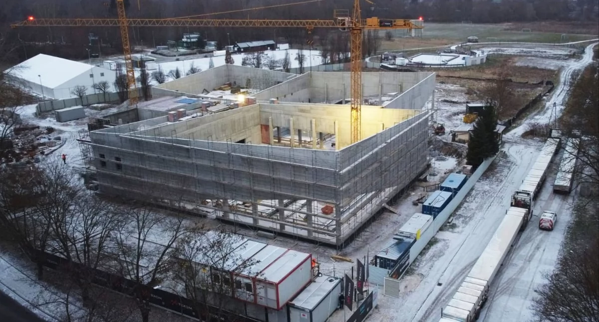 Budynek basenu wewnętrznego rośnie. Po prawej transport konstrukcji dachu wykonanego z drewna klejonego. Fot. Texom sp. z o.o.