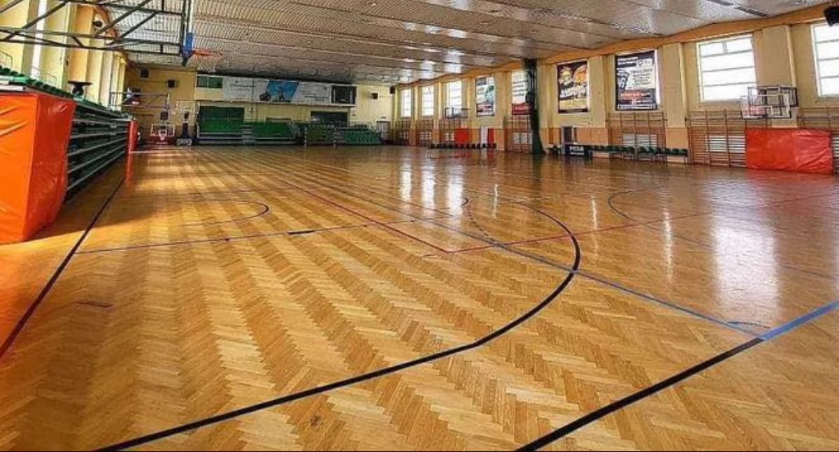Podłoga w hali sportowej przy ul. Mickiewicza 30 w Przemyślu jest w bardzo złym stanie technicznym. W kilku miejscach klepki zostały zniszczone, odczuwalny jest zapach pleśni i korozji biologicznej z powodu braku odpowiedniej izolacji przeciwwilgociowej poziomej podbudowy podłogi. Brak jest też odpowiedniej wentylacji przestrzennej „legarowej” podłogi. Fot. POSiR