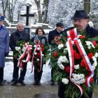 Burmistrz składa wieniec przed tablicą pamiątkową.